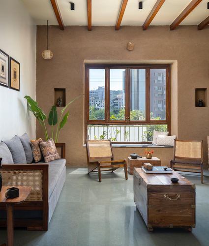 Living room with cane chairs, wooden trunk table, exposed beams and city-view window