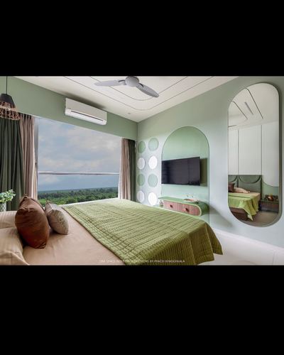 Sage green bedroom with arched TV niche, arched mirror, and window overlooking treetops