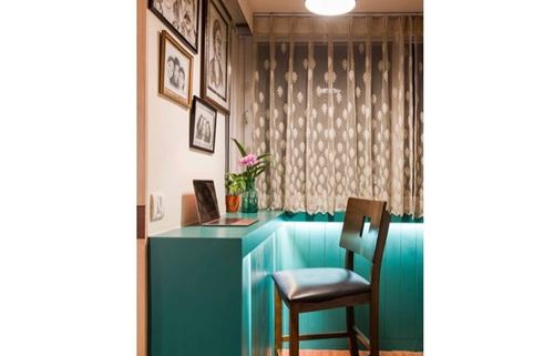 teal built-in desk nook with laptop, framed photos, lace curtain, and black wooden chair