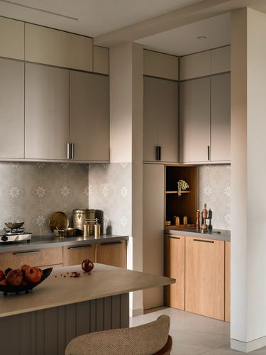 Ahmedabad apartment kitchen with wood cabinetry, patterned tile backsplash, brass vessels and pomegranates on island
