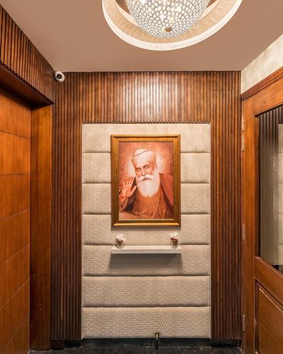Wood-panelled foyer with quilted upholstered niche framing a religious portrait, chandelier above
