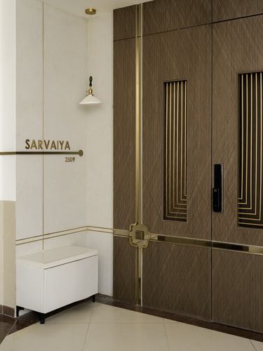 Entrance foyer with fluted brass-inlaid wooden double door and brass nameplate reading Sarvaiya