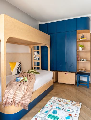 Child's bedroom with plywood bunk bed and curved navy blue built-in wardrobe