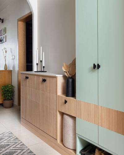 Foyer with mint green wardrobe, fluted wood cabinetry, and styled console with candle stand and vase