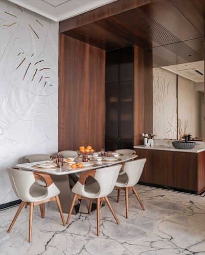 Dining room with marble table, cream chairs, carved leaf wall panel and wood-clad ceiling niche