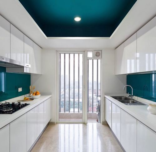 White galley kitchen with teal glass backsplash and matching ceiling, glass door to balcony with city view