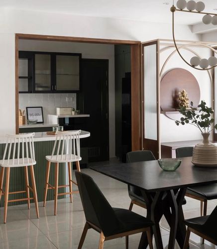 Open dining and kitchen area with black table, pendant chandelier, and circular pooja niche