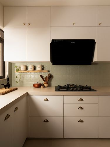L-shaped kitchen with beige cabinetry, sage tile backsplash, black chimney hood and hob