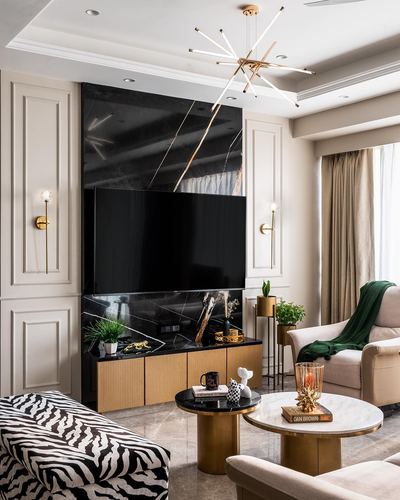 Art deco living room with black stone tv wall, brass fluted cabinet, sunburst chandelier, round marble coffee tables