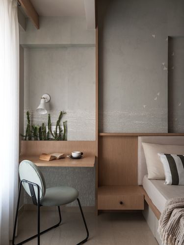 Bedroom corner with wood desk nook, cactus plants, and bed against bird-print wallpaper wall