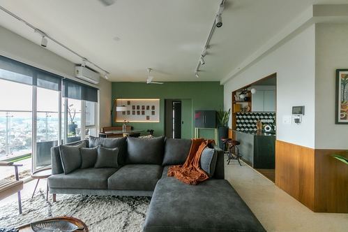 Living room with charcoal sectional, shag rug, fluted green wall and city skyline view