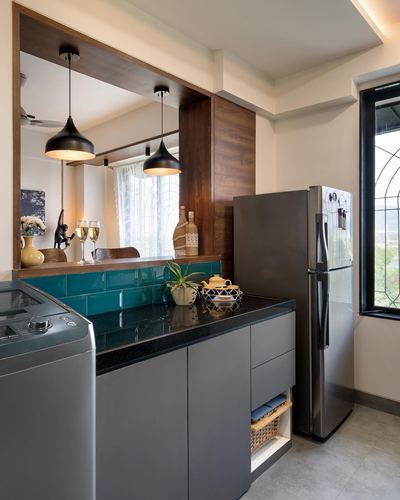 Compact kitchen with grey cabinetry, teal tile backsplash, black countertop and mirrored dining reflection