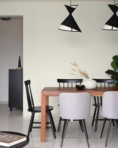 Dining table with black windsor chairs and grey upholstered chairs under two black cone pendant lights