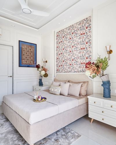 Bedroom with upholstered bed, floral fabric wall panel, and matching white nightstands with brass handles