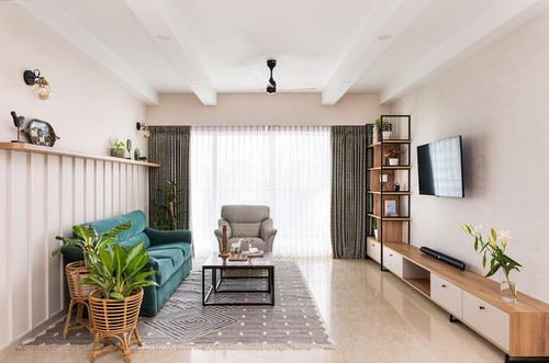 Living room with teal sofa, sheer curtains, ladder shelving unit and wood console tv unit