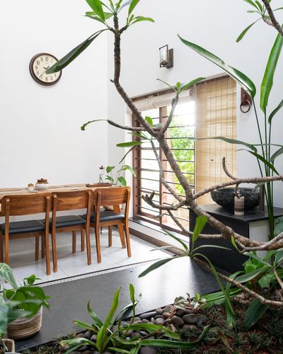 Dining table beside indoor plant courtyard with wooden window and stone basin