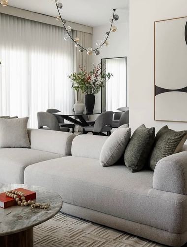 Neutral living room with boucle sectional, green pillows, and view to dining area beyond
