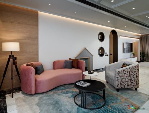 Living room with curved pink velvet sofa, round coffee tables, and arched wall niches