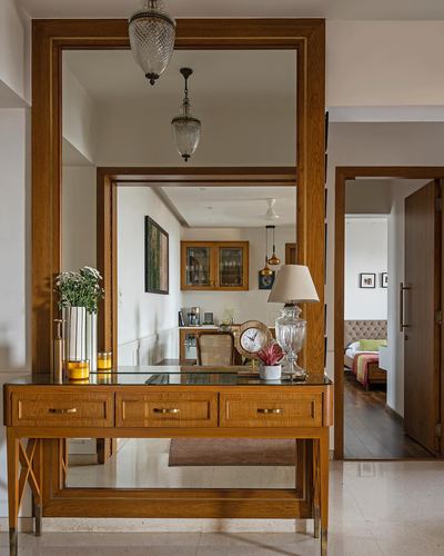 Wood-framed entryway mirror above a console table reflecting dining and bedroom beyond