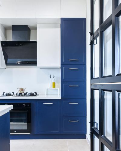 Navy blue and white modern kitchen with black chimney hood and steel-framed glass door