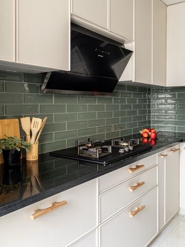 Kitchen counter with black granite, olive green subway tile backsplash, and black gas hob under a chimney hood
