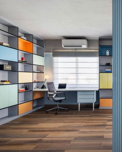 Home office with colorful modular shelving, blue desk, and wood-look flooring