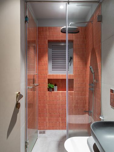 Terracotta-tiled glass shower stall with rain shower head and window niche in small bathroom