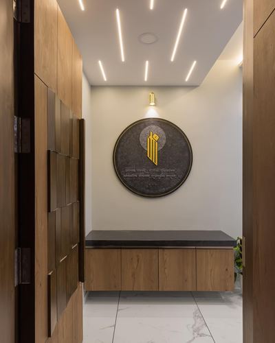 Entryway foyer with wooden wardrobe, circular stone plaque and floating wood console on marble floor
