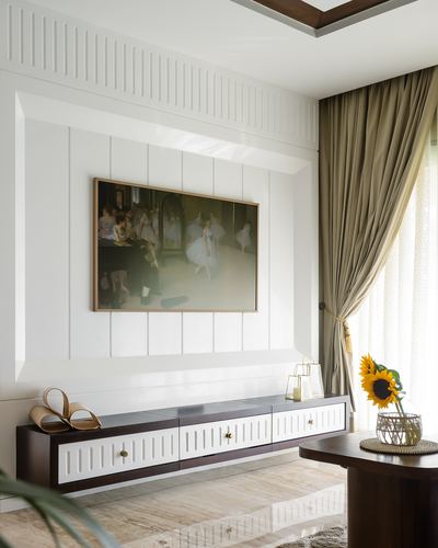 Living room with fluted white paneled wall, framed art, wood-and-white TV unit, and draped curtains beside marble floor