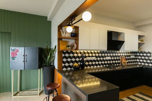 Kitchen with black countertop, geometric tile backsplash, globe pendant lights and ribbed green accent wall