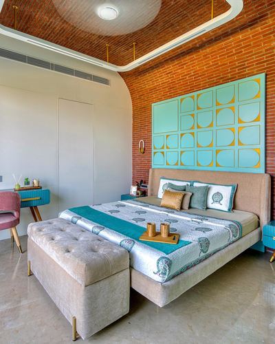 Bedroom with curved brick ceiling, teal geometric wall panel, beige upholstered bed and tufted bench.