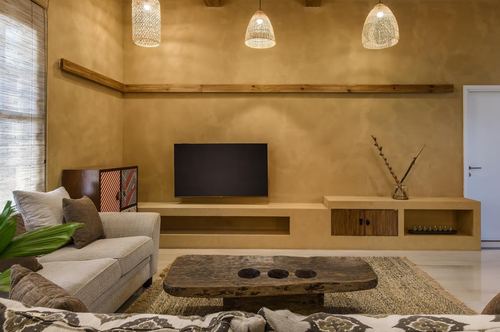 Earthy living room with plastered ochre walls, floating tv console, woven pendant lights and a raw-edge wood coffee table