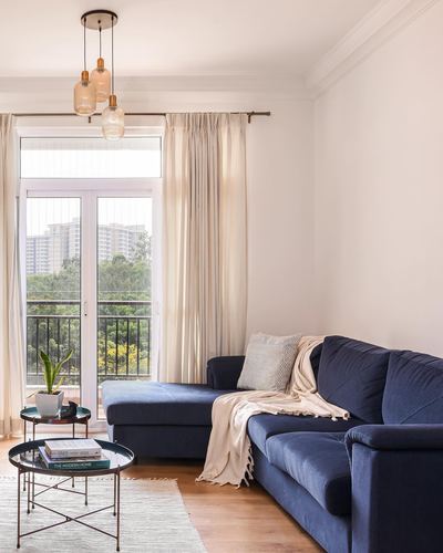 Navy sectional sofa in bright living room with balcony view and glass pendant lights