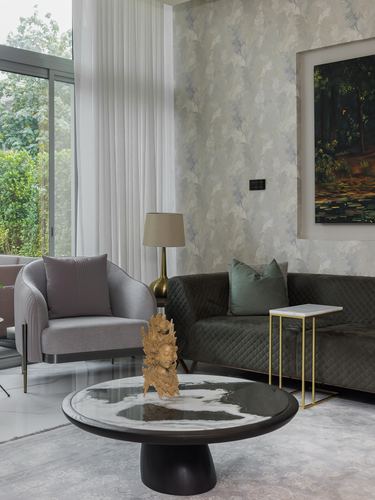 Living room corner with olive sofa, grey armchair, marble coffee table and framed painting