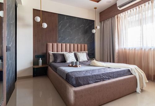 Bedroom with channel-tufted bed, marble accent wall, wood fluting, and hanging pendant lights