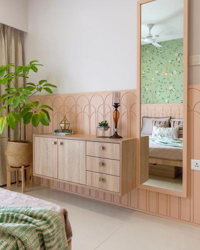 Floating wood sideboard beneath mirror against pink arched wall paneling in bedroom