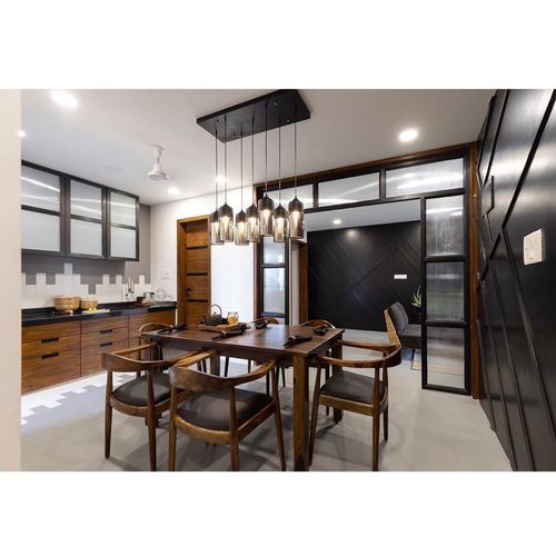 Dining room with wooden table, cane chairs, and a cluster pendant light against a black-framed backdrop
