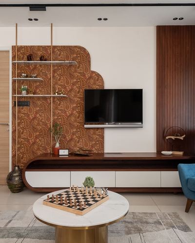 Living room with paisley-patterned arched wall panel, wood TV console, and round marble coffee table with chess set