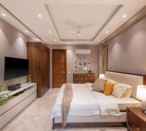 Modern bedroom with wood wardrobe, tv console, upholstered bed and gallery wall in neutral tones