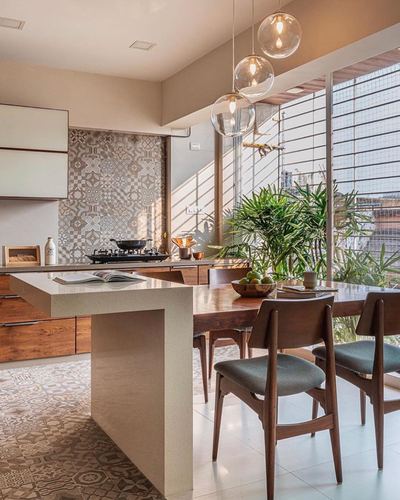 Kitchen island with patterned dado leading into a dining table under glass pendant lights