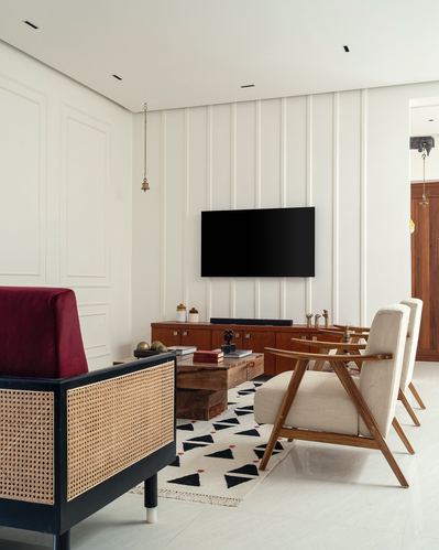 Living room with fluted white paneling, wooden console, cane sofa, and geometric rug