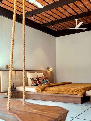 Bedroom with exposed brick ceiling, wooden platform bed, and a rope-hung wooden swing
