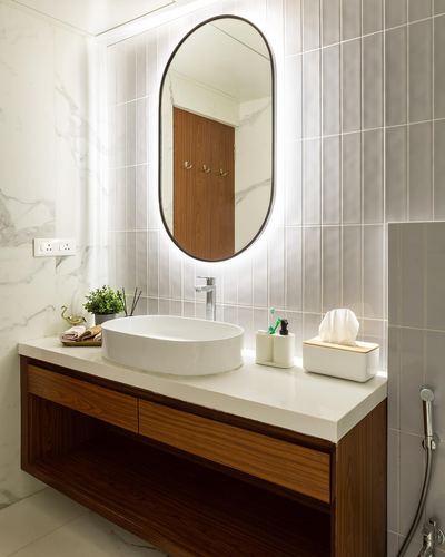 Bathroom vanity with oval backlit mirror, white vessel sink and wood cabinetry