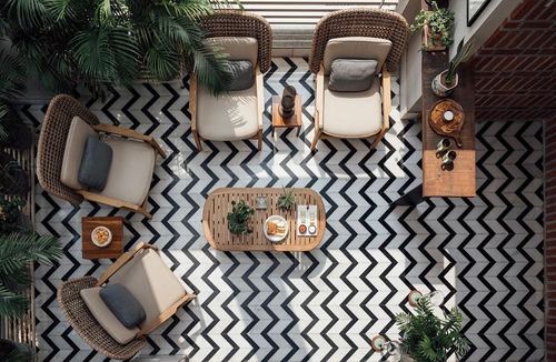 Overhead view of terrace seating on chevron-patterned tile with rattan chairs and potted palms