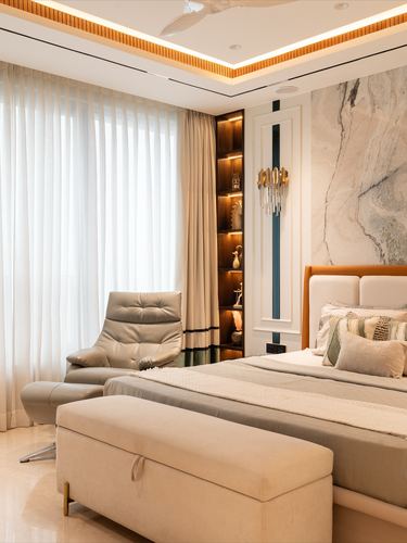 Bedroom with marble feature wall, tan leather bed, backlit display niche and sheer curtains