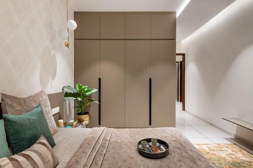 Muted taupe bedroom with tall wardrobe, textured bedding, and a hallway view beyond
