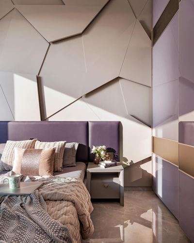 Bedroom with faceted geometric wall panel, purple upholstered headboard, and sunlight casting sharp shadows