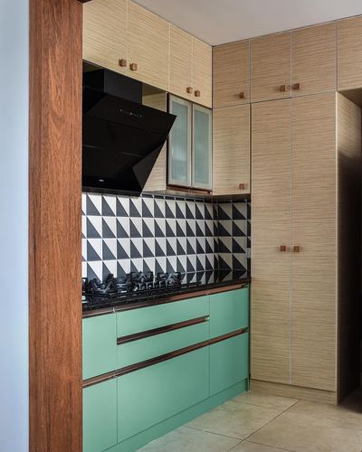 Kitchen with sage green cabinets, black triangle tile backsplash, wood-grain overhead cabinetry