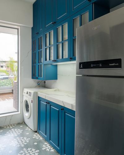 Teal cabinetry kitchen with marble counter, glass-front cabinets, washing machine and steel fridge