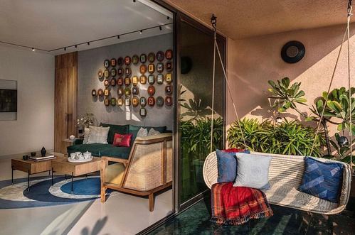 Living room with cane sofa, framed wall art, and adjoining balcony with hanging swing chair